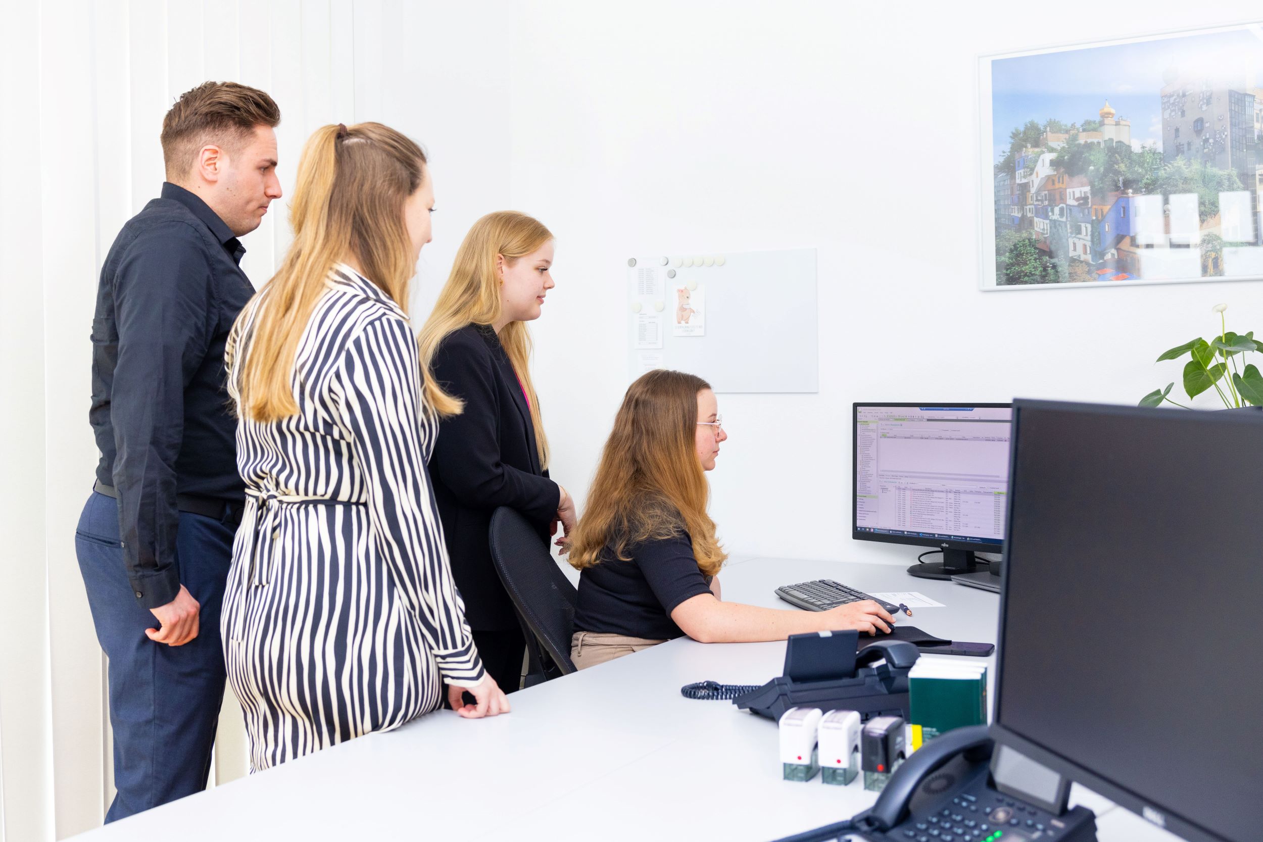 Teammeeting: Mehrere Mitarbeitende vor PC am Schreibtisch im Büro